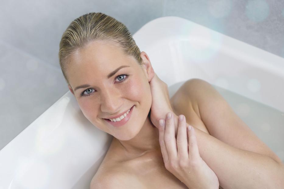 Eine lächelnde Frau entspannt in einer Badewanne.