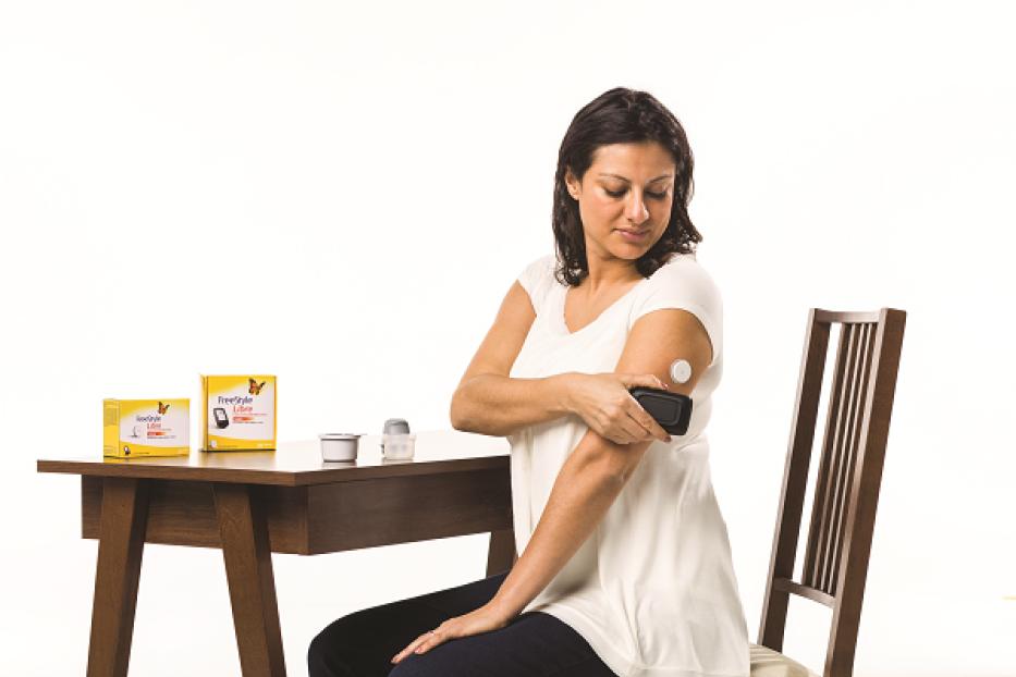 Eine Frau misst ihren Blutzucker mit einem FreeStyle Libre Lesegerät.