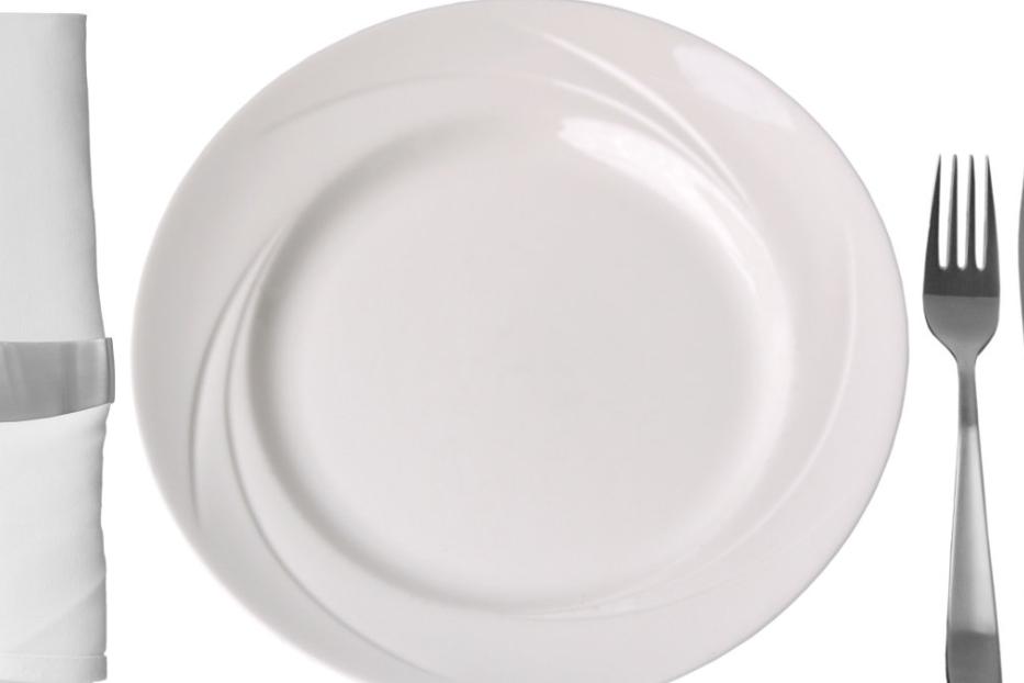Ein leerer, weißer Teller mit Besteck und einer Serviette.