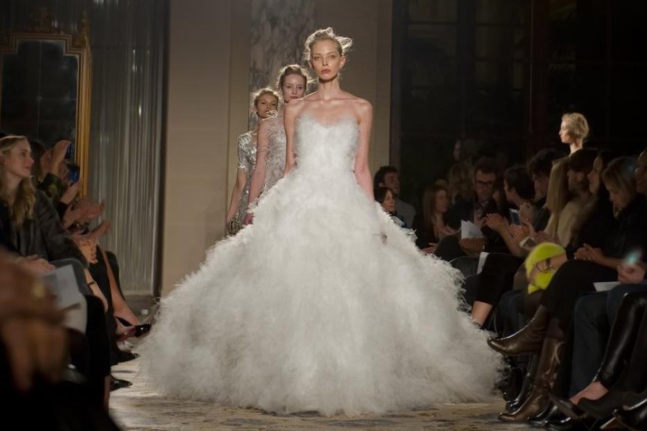Eine Frau in einem weißen Brautkleid auf einem Laufsteg während einer Modenschau.