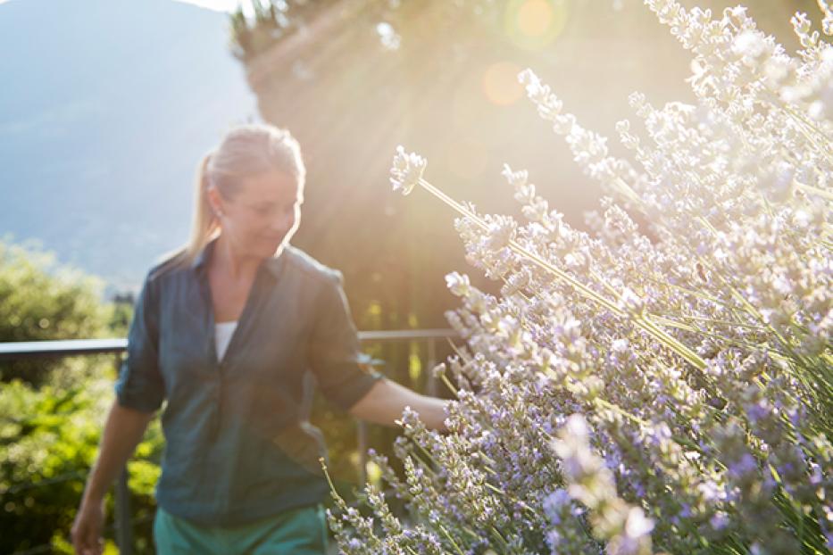 Eine Frau betrachtet Lavendelblüten im Garten.