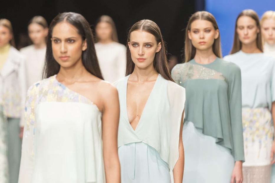 Models präsentieren pastellfarbene Kleidung auf einem Laufsteg.
