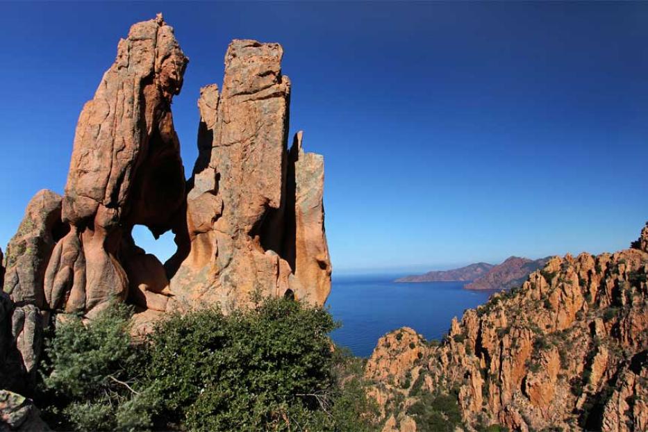 Eine Felsformation mit einem herzförmigen Loch an der Küste Korsikas.