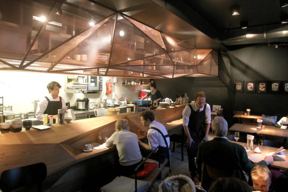 Blick in ein Restaurant mit Gästen und Personal hinter einer Bar.