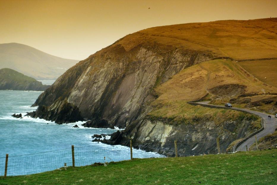 Eine Küstenstraße schlängelt sich an einer Klippe entlang, mit Blick auf das Meer.