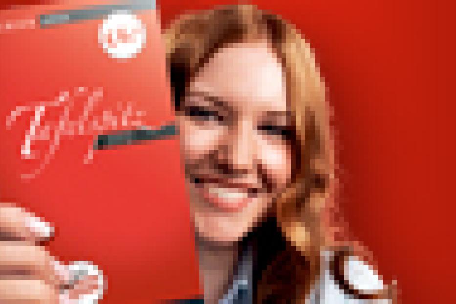 Eine lächelnde Frau hält eine rote Teekiste der Marke Teekanne in die Kamera.