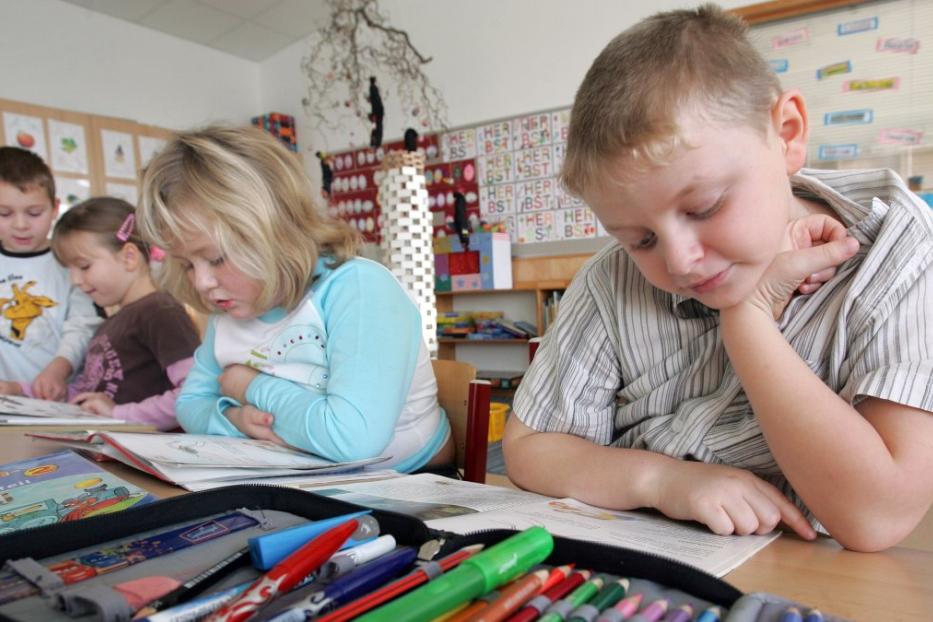 Eine Gruppe von Grundschulkindern sitzt an einem Tisch und liest Bücher.