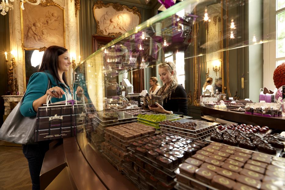Eine Kundin betrachtet die Pralinenauswahl in einem edlen Schokoladengeschäft von Dominique Persoone.