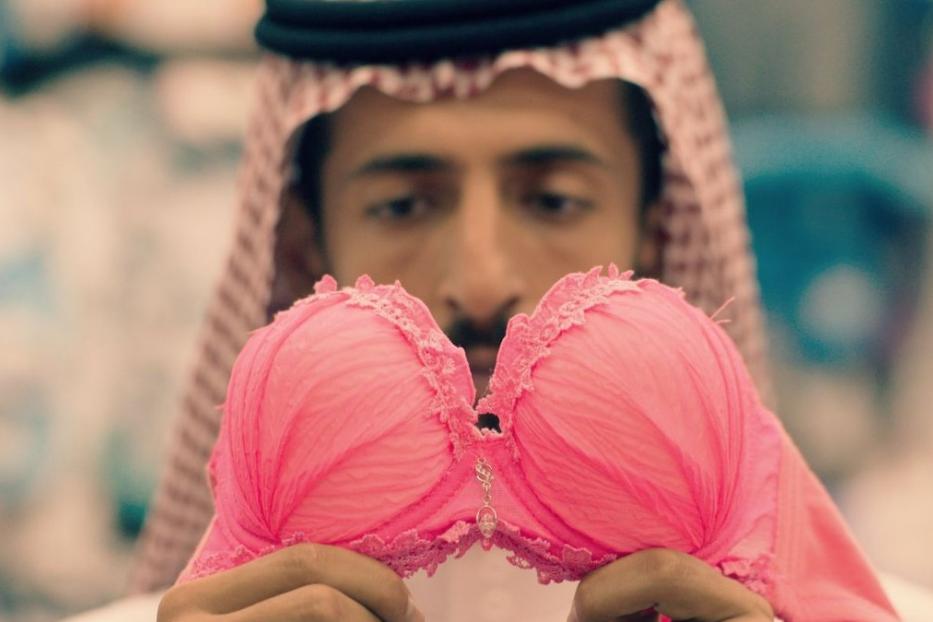 Ein Mann im traditionellen Gewand hält einen rosa BH in seinen Händen.