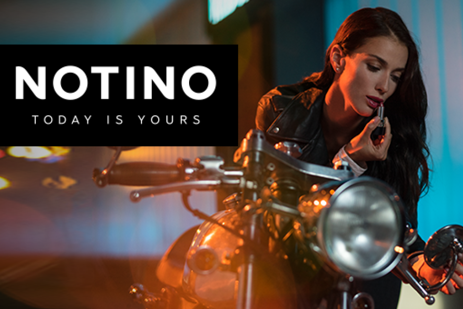 Eine Frau mit Lederjacke trägt Lippenstift auf einem Motorrad.