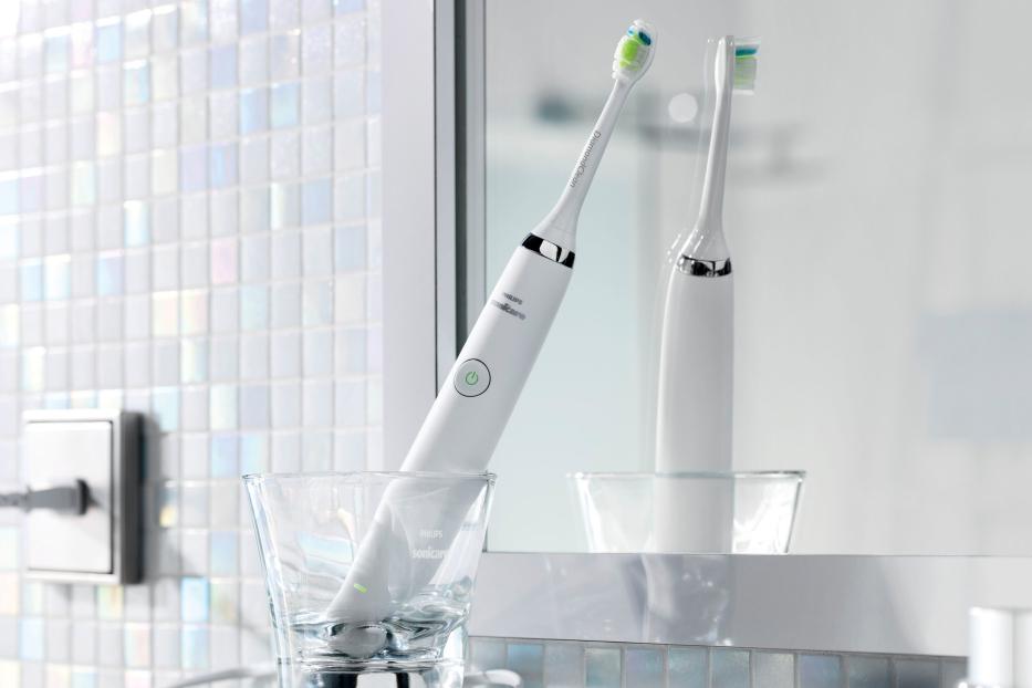 Eine elektrische Zahnbürste von Philips Sonicare steht in einem Glas im Badezimmer.