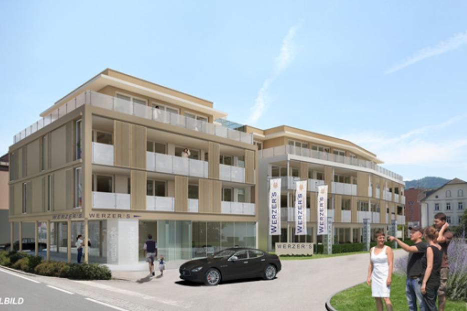 Ein modernes Wohngebäude mit dem Schriftzug „Werzer's“ und einer Gruppe von Menschen davor.