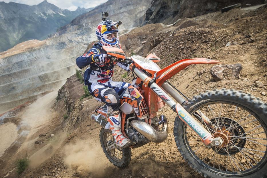 Ein Motocross-Fahrer fährt eine steile, staubige Piste hinunter.