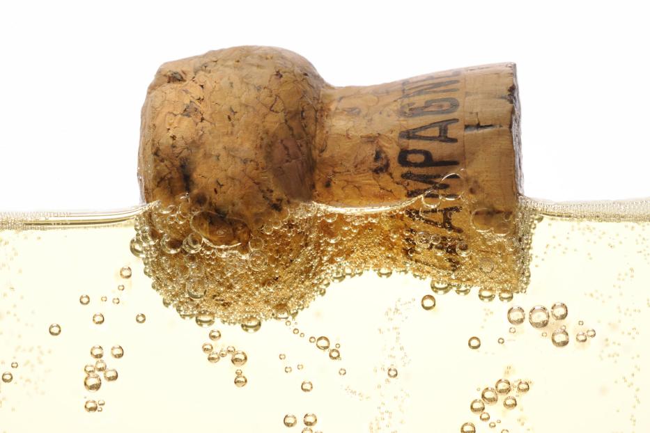 Ein Champagnerkorken schwimmt in einem Glas Sekt.
