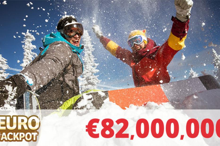 Zwei Snowboarder werfen im Schnee die Arme in die Luft.