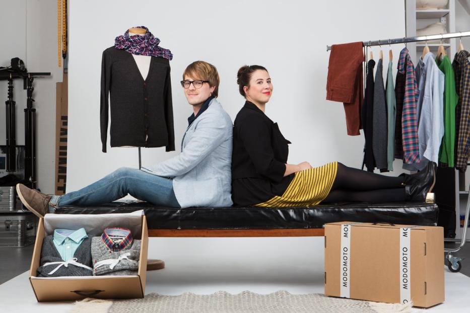 Ein Mann und eine Frau sitzen Rücken an Rücken auf einer Bank in einem Bekleidungsstudio.