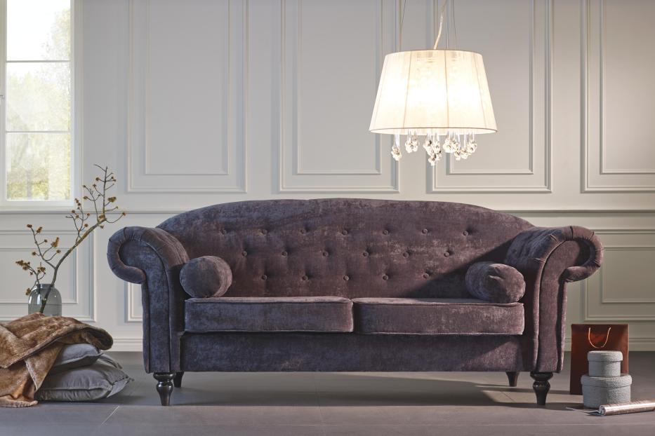 Ein violettes Sofa mit Knöpfen und runden Kissen in einem eleganten Wohnzimmer.