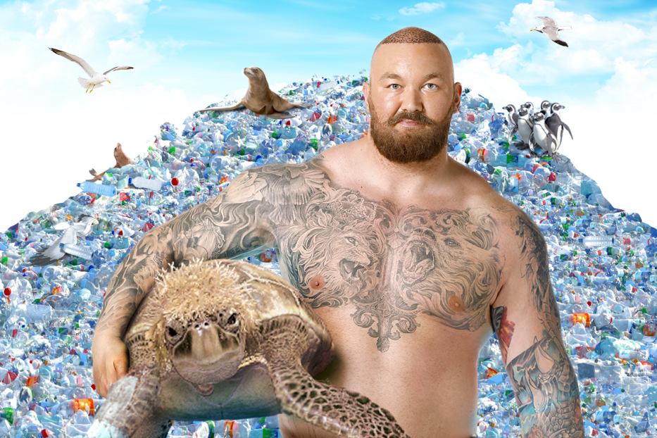 Ein tätowierter Mann hält eine Schildkröte vor einem Berg aus Plastikmüll, auf dem Seevögel und Robben sitzen.