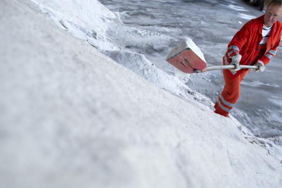 Ein Arbeiter schaufelt Salz mit einer Schaufel.