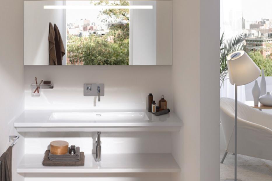 Ein modernes Badezimmer mit Waschbecken, Spiegel und einer Stehlampe im Hintergrund.