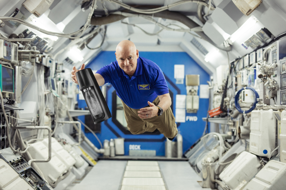 Astronaut Scott Kelly schwebt mit einer sprudelnden Wasserflasche in der Internationalen Raumstation.