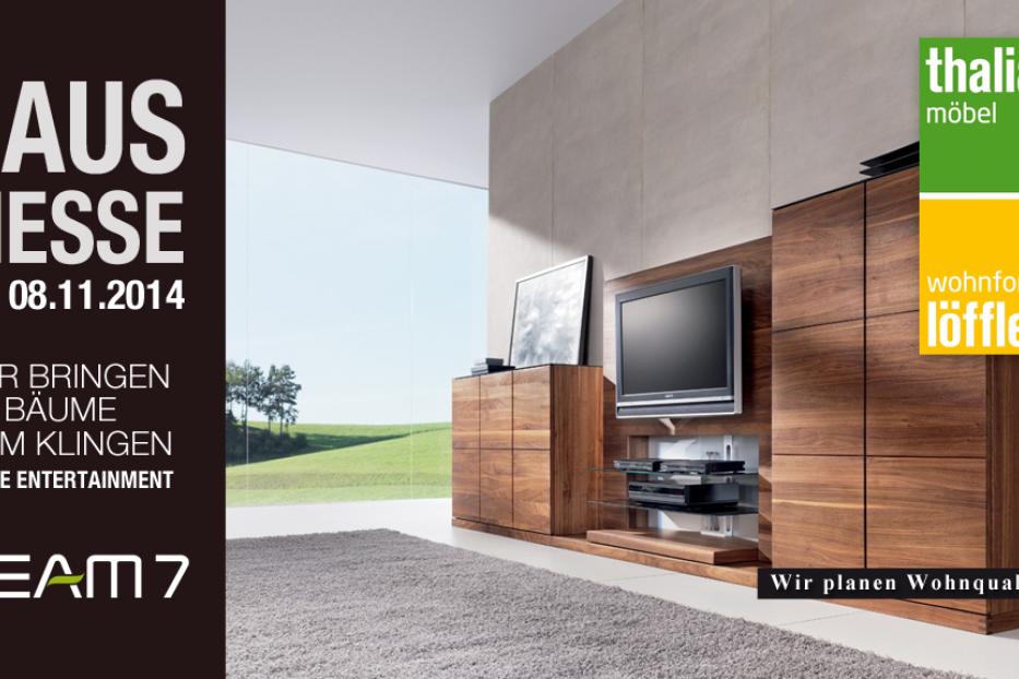 Ein modernes Wohnzimmer mit Holzmöbeln und einem großen Fenster mit Blick ins Grüne.