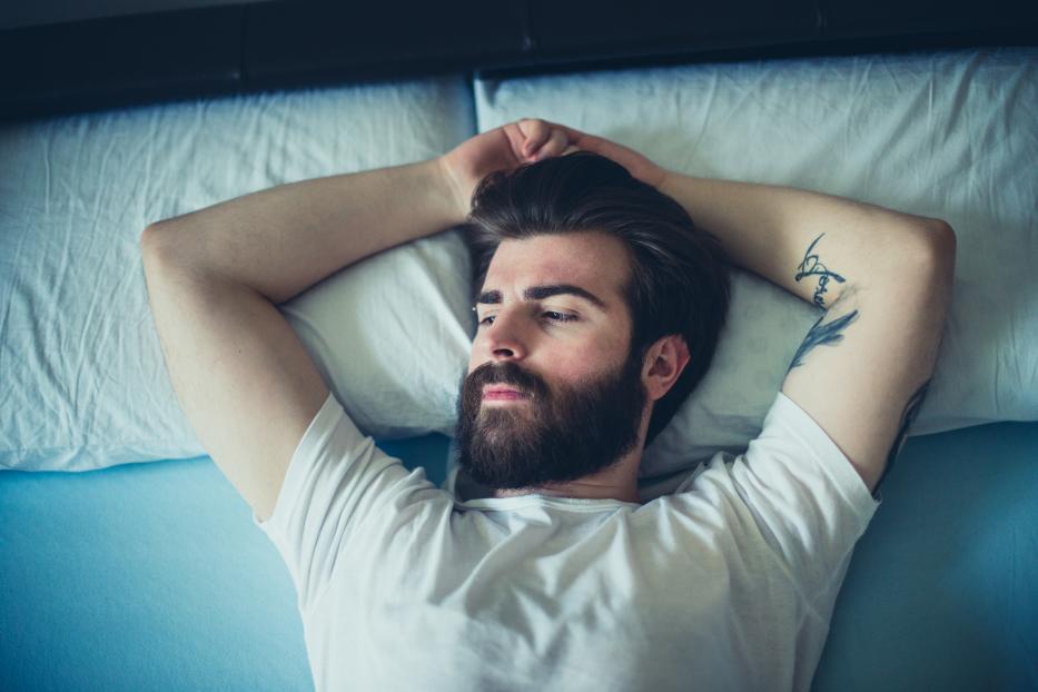 Portrait of sad bearded man lying down in the bad