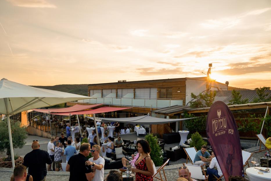 Eine Gruppe von Menschen versammelt sich im Freien bei Sonnenuntergang für eine Veranstaltung.