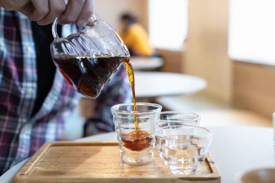 Tee wird aus einer Kanne in ein Glas geschüttet