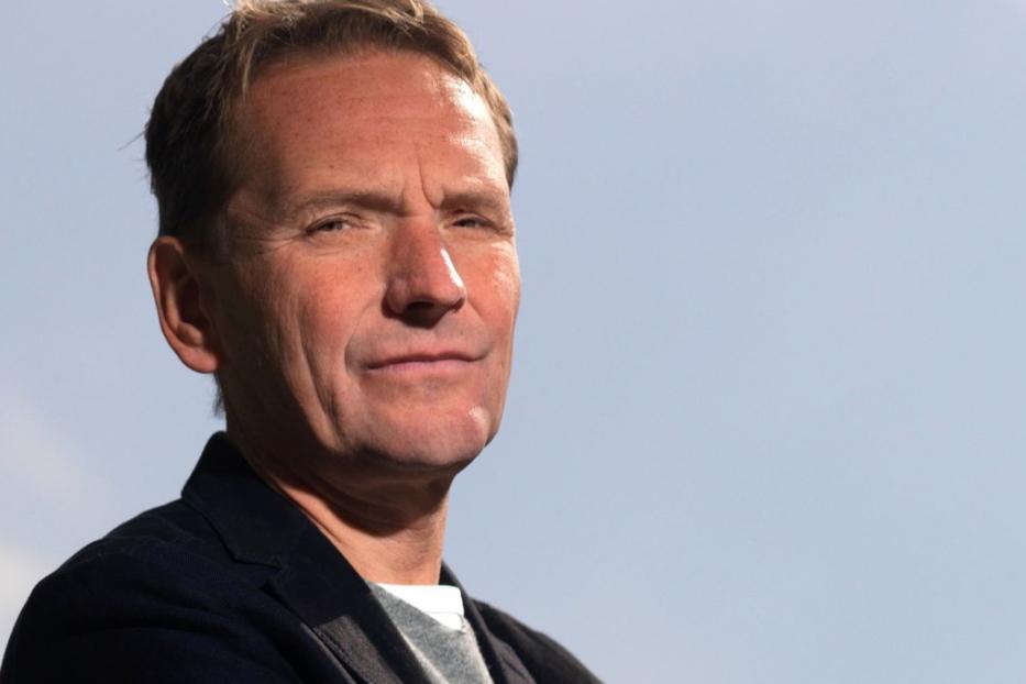 Porträt eines Mannes vor einem hellblauen Himmel.