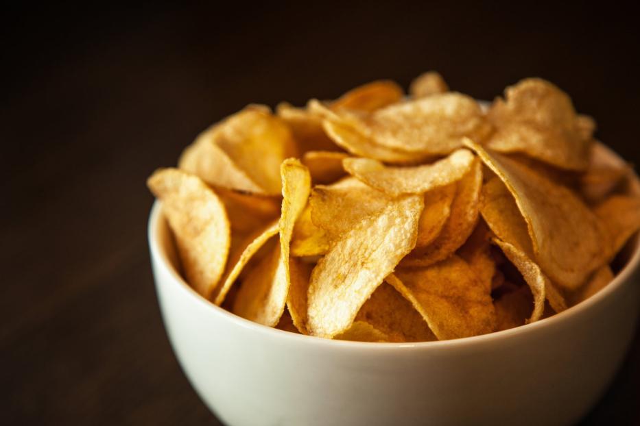Eine Schüssel ist gefüllt mit goldgelben Kartoffelchips.