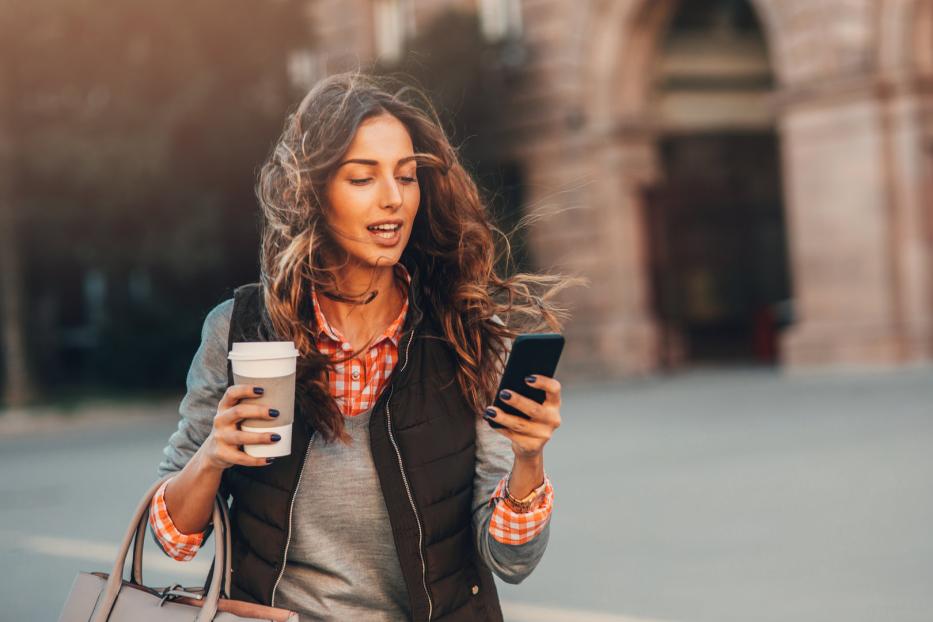 Frau mit Handy und Kaffee