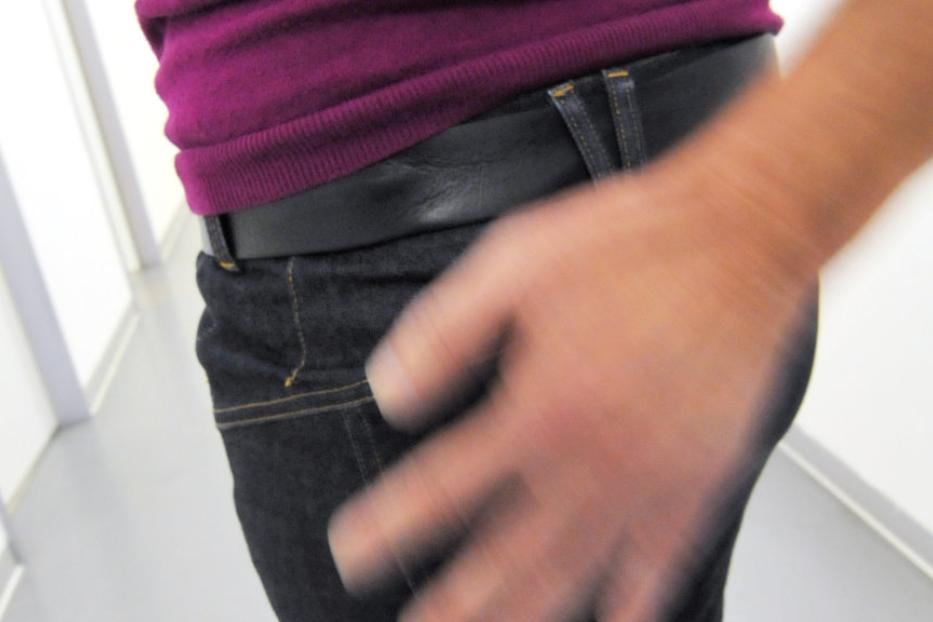 Eine Person in Jeans und einem lila Oberteil mit einer Hand in Bewegung.