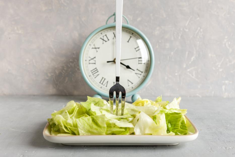 Ein Teller mit Salat vor einer Uhr.