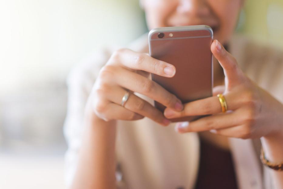 Eine Frau hält ein Smartphone in der Hand. 