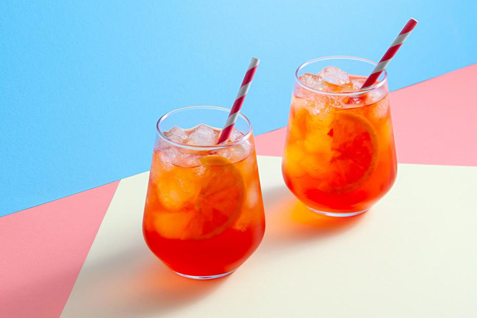 Spritz Cocktail in glasses with ice and orange slice on trendy colorful background. Creative minimal concept