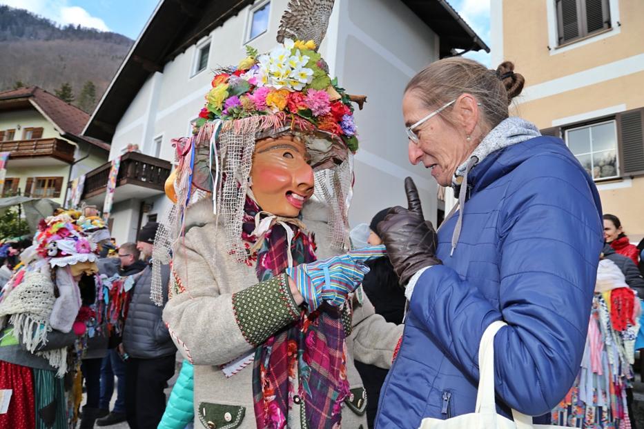 Eine Frau in traditioneller Faschingsmaske interagiert mit einer anderen Frau.
