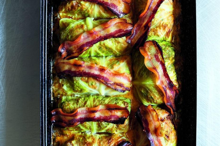 Kohlrouladen mit Speckstreifen in einer schwarzen Auflaufform.