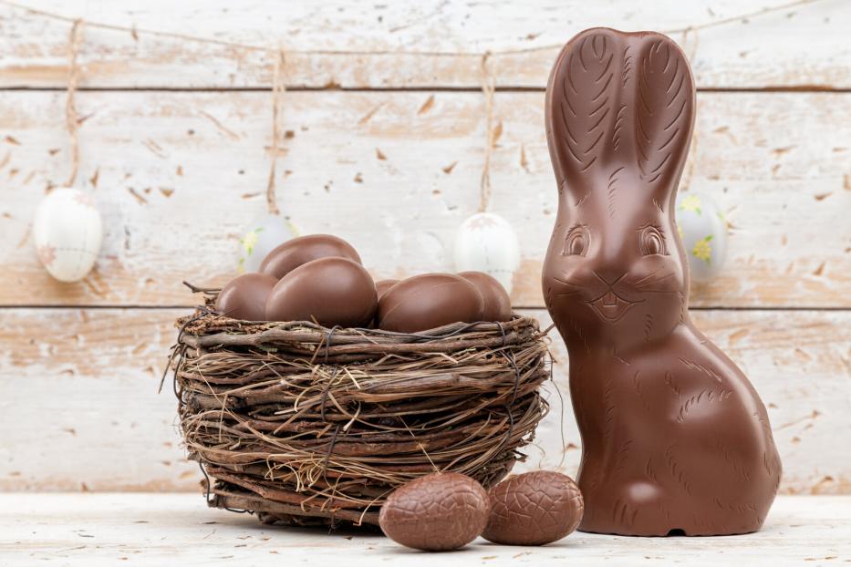 Chocolate Easter bunny, eggs and sweets on rustic background