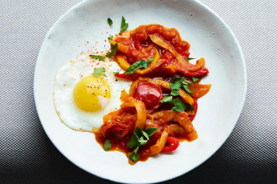 Ein Teller mit Spiegelei, Paprikagemüse und ein Stück Brot.