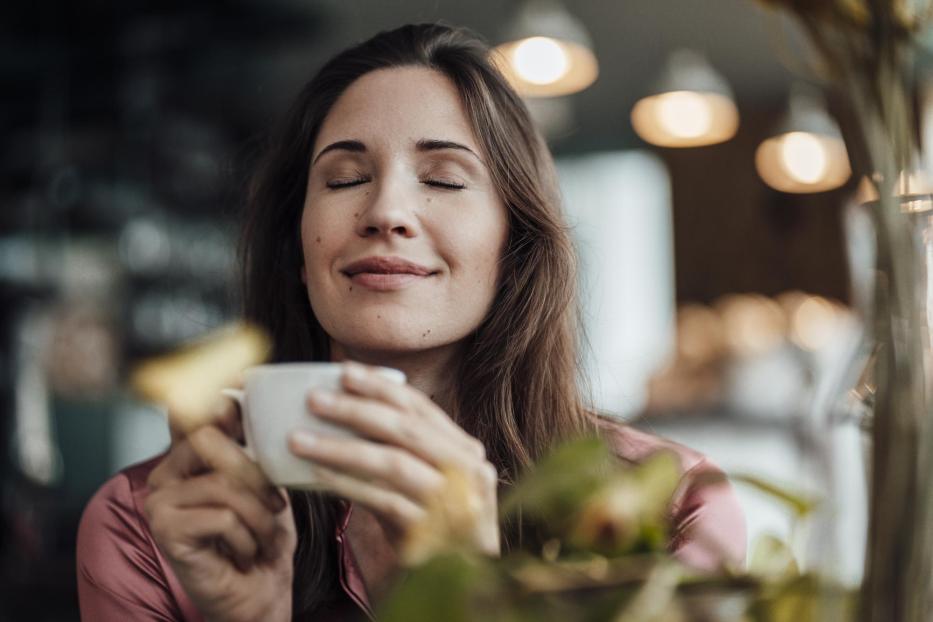 Smiling businesswoman smelling coffee in cafe - Stock-Fotografie