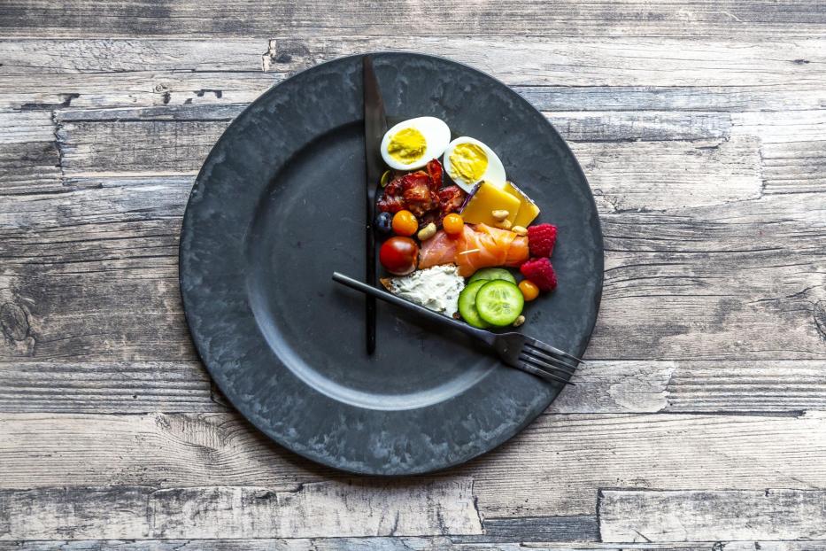 Variety of food on round plate, intermittent fasting - Stock-Fotografie