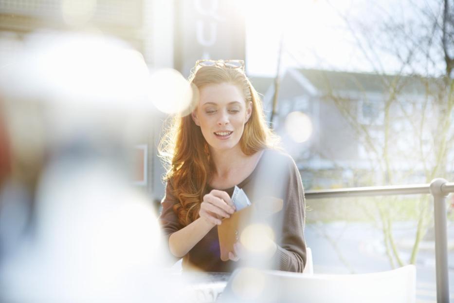 Young woman taking notes out of her purse - Stock-Fotografie