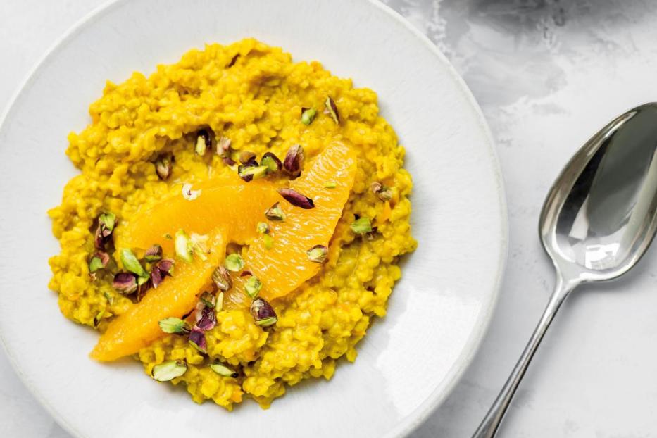 Karotten-Orangen-Porridge mit Pistazien auf zwei Tellern.