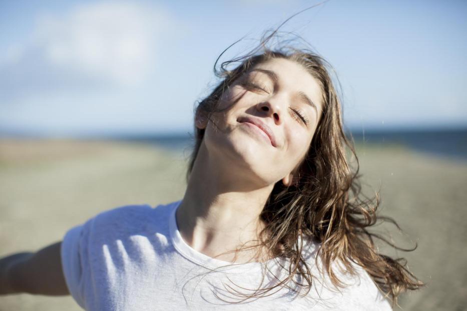 Young woman with eyes closed smiling on a beach - Stock-Fotografie