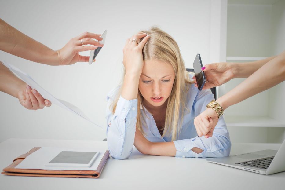 Junge Frau sitzt nach dem Urlaub wieder im Büro und ist gestresst.