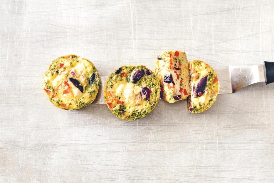 Drei Eierkuchen mit Oliven und Paprika liegen auf einem Messer.