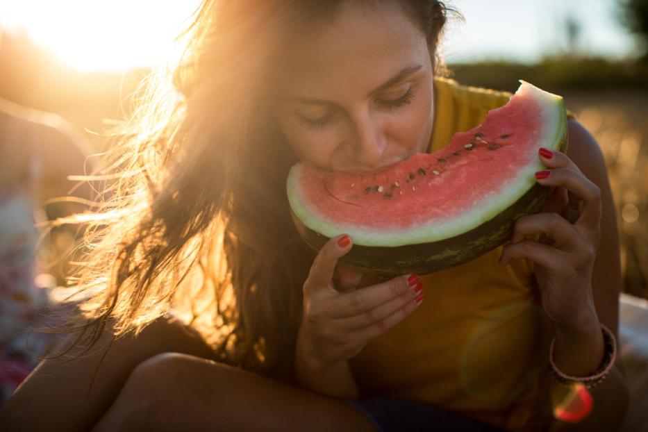 Junge Frau isst Wassermelone im Freien - Stock-Fotografie