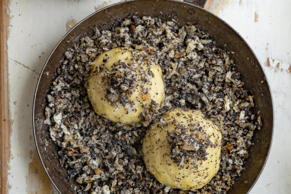 Mohnnudeln in einer Pfanne, daneben eine Tasse mit gelber Sauce.