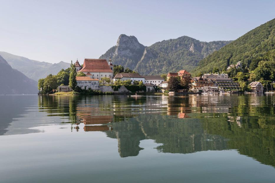 Tiefer See und hohe Berge: Das Kloster Traunkirchen mit dem Seehotel Das Traunsee (rechts).